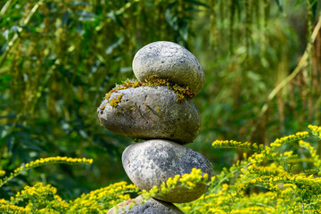 Fototapeta na wymiar Stack of moss and lichen covered river rocks in a summer garden, as a nature background 