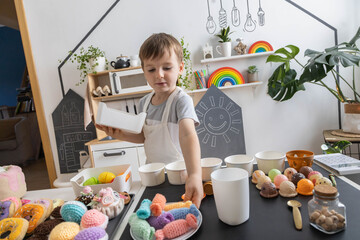 Male baby chef in apron posing at childish kitchen cafe public catering food sweet toys imitation