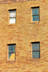 Close up view of four windows on the side of brick building facade in the midday sun in the city