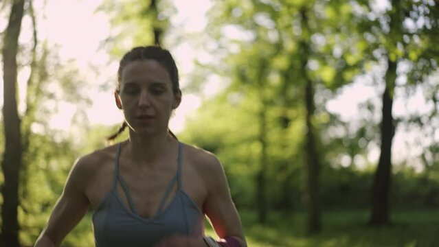 Young athletic woman running in the sunny forest. Healthy lifestyle concept. Slow motion.