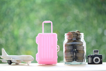 Model camera and gold coin money in the glass bottle on natural green background,Saving planning...