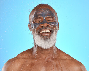 Fototapeta na wymiar Skincare, water and black man with mask for facial on blue background in studio for wellness, spa and cleanse. Dermatology, cleaning and senior male with face mask, skin treatment and water splash
