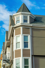 Light and dark brown slatted wood building with white accent paint around windows and near roof on modern building exterior