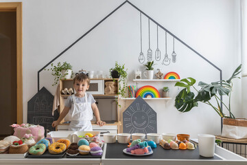 Male baby chef in apron posing at childish kitchen cafe public catering food sweet toys imitation