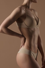 Obraz premium Thin young woman in underwear on beige background