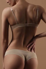 Obraz premium Thin young woman in underwear on beige background
