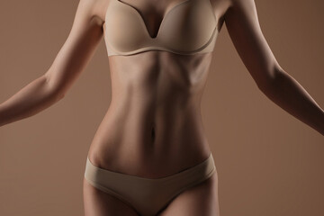 Fototapeta premium Thin young woman in underwear on beige background
