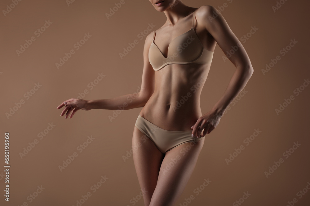 Wall mural thin young woman in underwear on beige background