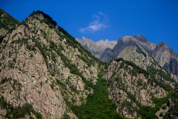Fototapeta na wymiar Rocky mountains with vegetation against the sky. Mountain landscape.