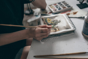 Young redhead woman artist drawing with water colors