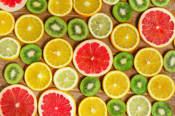 Fototapeta na wymiar frame with slice of oranges, lemons, kiwi, grapefruit pattern isolated on wooden background. Flat lay, top view