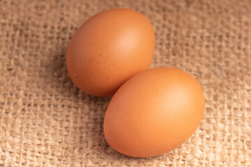 Three fresh chicken eggs on brown background