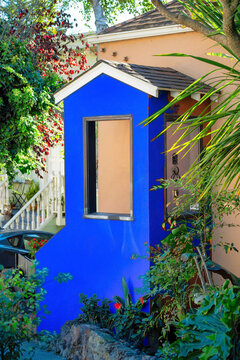 Blue exterior paint on mini house facade near front door entrance in yard on patio