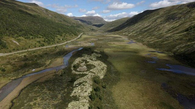  Aerial shot of Norwegian valley near Rondone national park. Summertime valley. The Norwegian valley with mountain ranges and turquoise water

