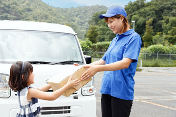 宅配便、宅配サービスで荷物を子供に届けている宅配ドライバーの女性