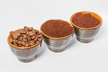 three small saucers with coffee beans, ground coffee and cocoa on a white background.