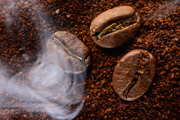 ground coffee and three beans in a light smoke.