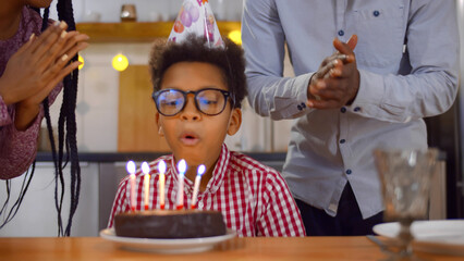 Close up of African-American mother and father congratulating preteen son holding birthday cake