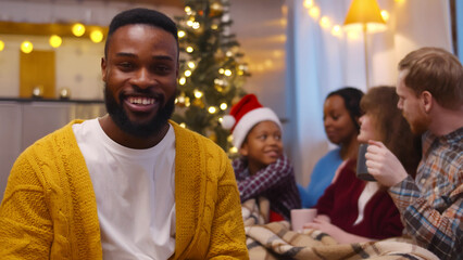African-American young man having video call with friends and son celebrating christmas on background