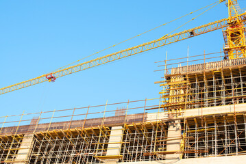 Crane and building construction site against blue sky. Construction of new residential high-rise building