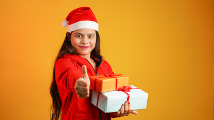 Beautiful young woman with Christmas gift box, Asian Indian girl wearing Santa cap isolated over colour studio background