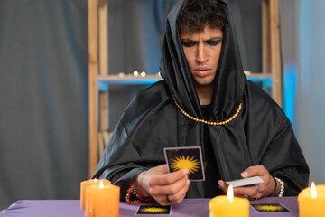 fortune teller man reading tarot cards on a table with candles.