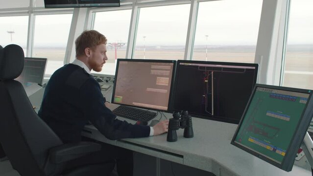 Security officer working on computer with monitors in system control room. Realtime