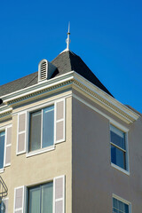 Obraz premium Beige stucco building with brown roof and white accent paint around windows and spire atop roof in midday say with clear sky