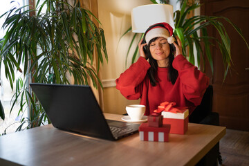 Relaxed woman businessman freelancer listening to the music on laptop, podcast, e-book, radio playlist, musical track in headphones while resting on Christmas eve at home