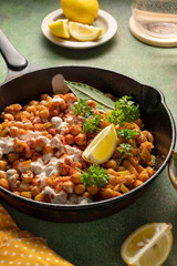 Cooked Chickpea in frying pan with curry and spices, homemade vegan chickpeas, healthy food, colorful green background