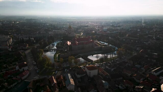 Panorama aerial drone flight over castle Cetatea Făgărașului in Făgăraș, Rom&acirc;nia during sunset in autumn - Fagaras in Romania is a touristic city - water reflection - bird view