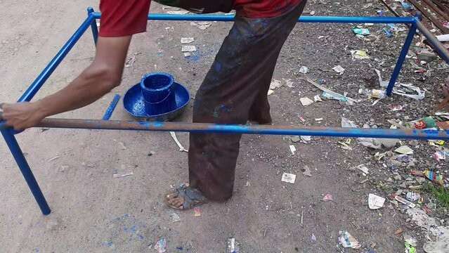 The worker is painting the traditional khatiya pipe in India. Rope Bed 