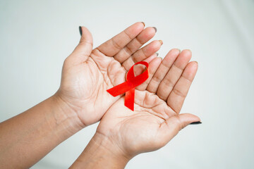 Worlds HIV Aids Day 2022-2023, Closeup hands holding red aids awareness ribbon on white background concept of world aids day HIV