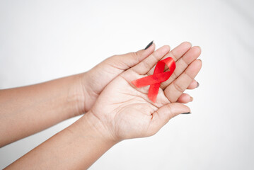 Worlds HIV Aids Day 2022-2023, Closeup hands holding red aids awareness ribbon on white background concept of world aids day HIV