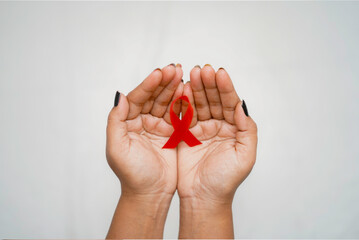 Worlds HIV Aids Day, A top view Closeup hands holding red aids awareness ribbon on white background concept of world aids day HIV