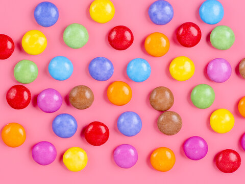 brightly colored sugar coated confectionary chocolate on a pink background