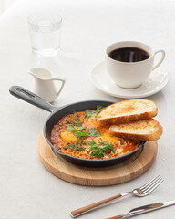 Pan of cooked shakshuka middle eastern dish with bread