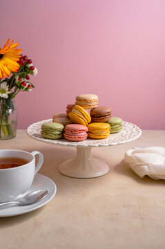 Colorful macaroons, french delicious cookies on cake stand, pink background. Sweet,