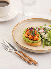 Portion of avocado toast with grilled shrimp and salad