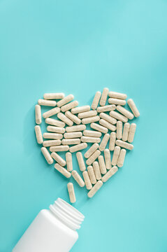 White pill bottles on blue background. Heart desease, treatment concept. Food supplements, vitamins and medicaments