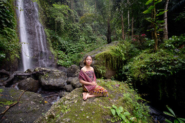 Girl in classic Balinese clothes pose at the Yeh Labuh waterfall