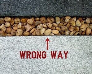 walk way with text inscription and sign to WRONG WAY, concept of lack or setting goals incorrect...