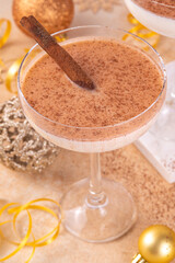 Eggnog Martini cocktail with cinnamon and nutmeg, with golden Christmas decorations and bokeh effect, copy space