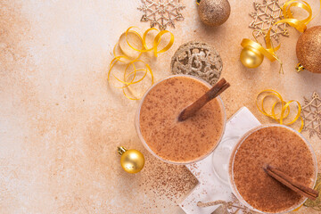 Eggnog Martini cocktail with cinnamon and nutmeg, with golden Christmas decorations and bokeh effect, copy space