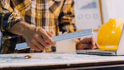 Two colleagues discussing data working and tablet, laptop with on on architectural project at construction site at desk in office