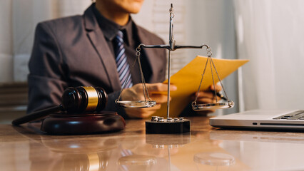 Justice and law concept.Male judge in a courtroom with the gavel, working with, computer and docking keyboard, eyeglasses, on table in morning light