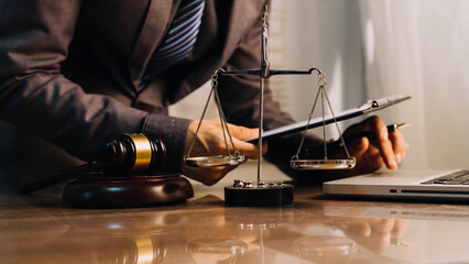 Justice and law concept.Male judge in a courtroom with the gavel, working with, computer and docking keyboard, eyeglasses, on table in morning light