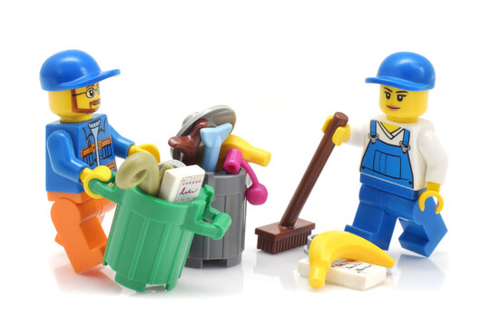 Lego minifigure of cleaning service is removing a garbage in trash cans closed up isolated on white background. Editorial illustrative image of popular toy.