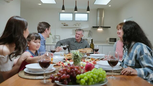 Multi-ethnic big family having dinner, enjoy evening party in house.