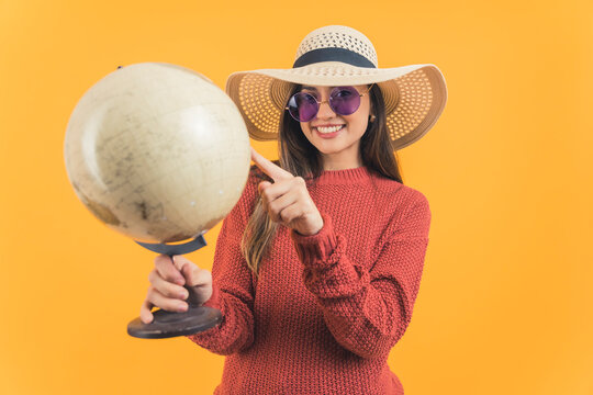 Young girl wearing a sun hat and sunglasses holding a globe. High quality photo